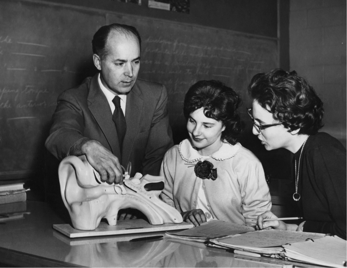 Teacher, Mr Nightingale, showing a model of the ear to two students: Gail McGreevy & Bev Mason (1960.)
